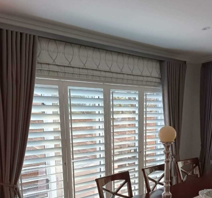 White plantation shutters with grey drapes in a Gauteng dining room, a We Do Blinds install.