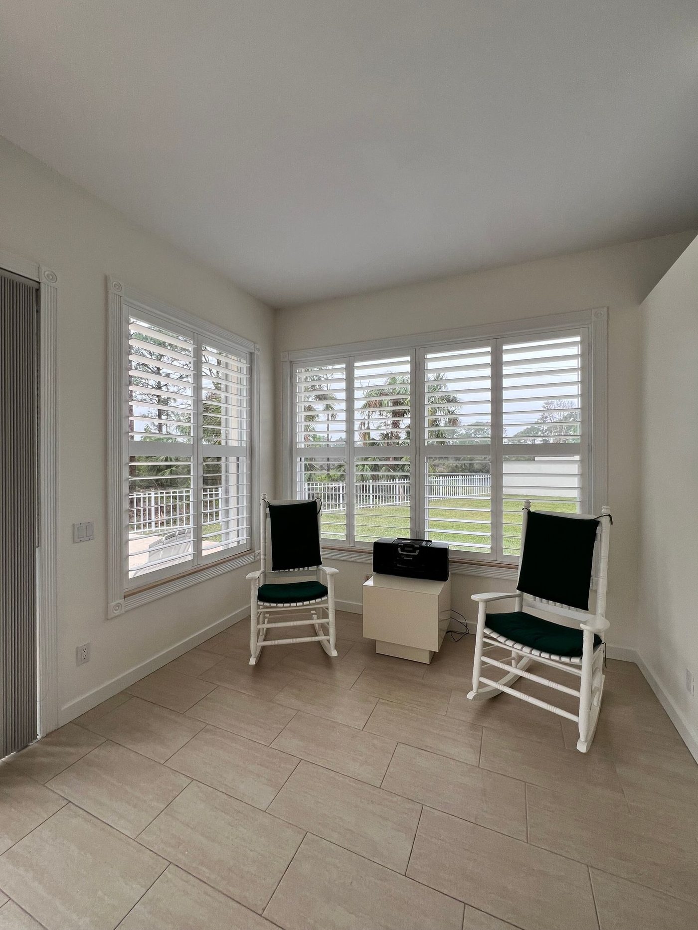 Sunroom with white plantation-style shutters and rocking chairs — stock photograph, not our job.